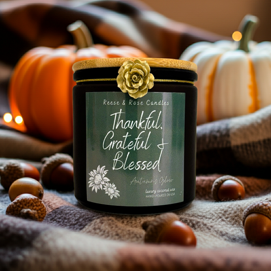Jar of candles with a 'Thankful, Grateful, Blessed' label, surrounded by pumpkins and acorns on a textured fabric background.