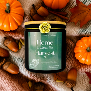Candle labeled 'Home is where the Harvest is' surrounded by pumpkins, leaves, and acorns on a textured fabric background.