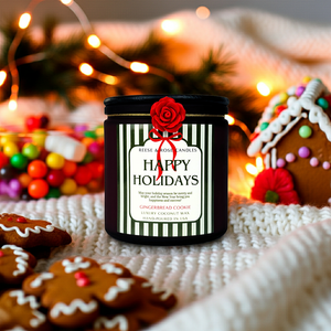 Candle with 'Happy Holidays' label surrounded by gingerbread cookies and a gingerbread house in a festive setting.